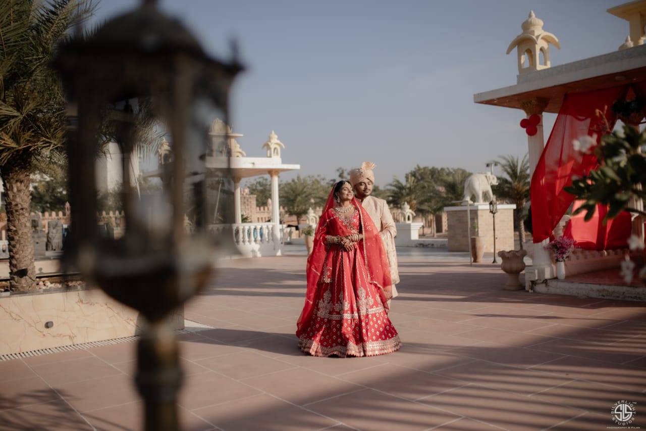 Modern Indian wedding with bride in pastel lehenga and groom in ivory sherwani under floral mandap decor.
